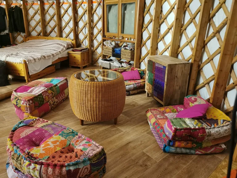 The lived-in interior of Barna's own 80 m² yurt: textiles, cushions, a cosy living area