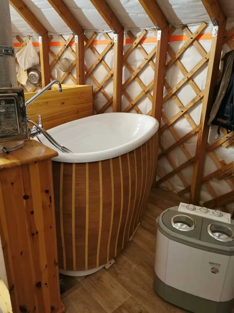 The zoned interior of the yurt: bathing corner, golden wood and roof window