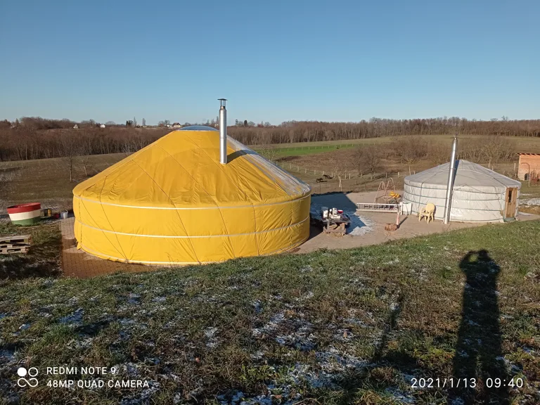 Barna's own hand-built 10-metre yurt in winter, in a snowy landscape under a blue sky