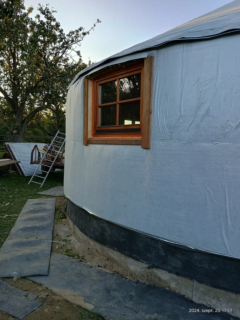 The white covering of the yurt with a wooden-framed roof window, a close detail